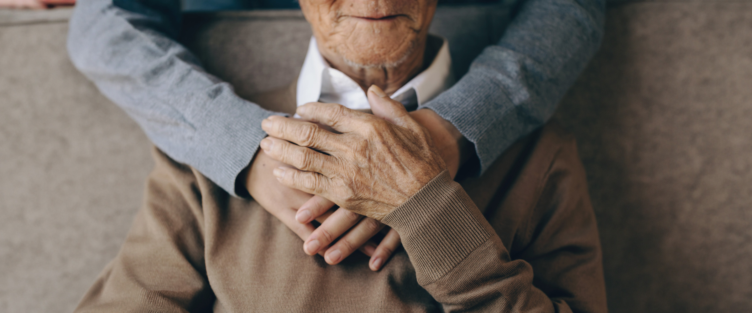 Happy healthcare worker hugging a senior man at home and support encouraging old people. A happy patient is holding the caregiver for a hand while spending time together. Elderly health care ...